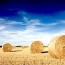 Straw bales on farmland with blue cloudy sky